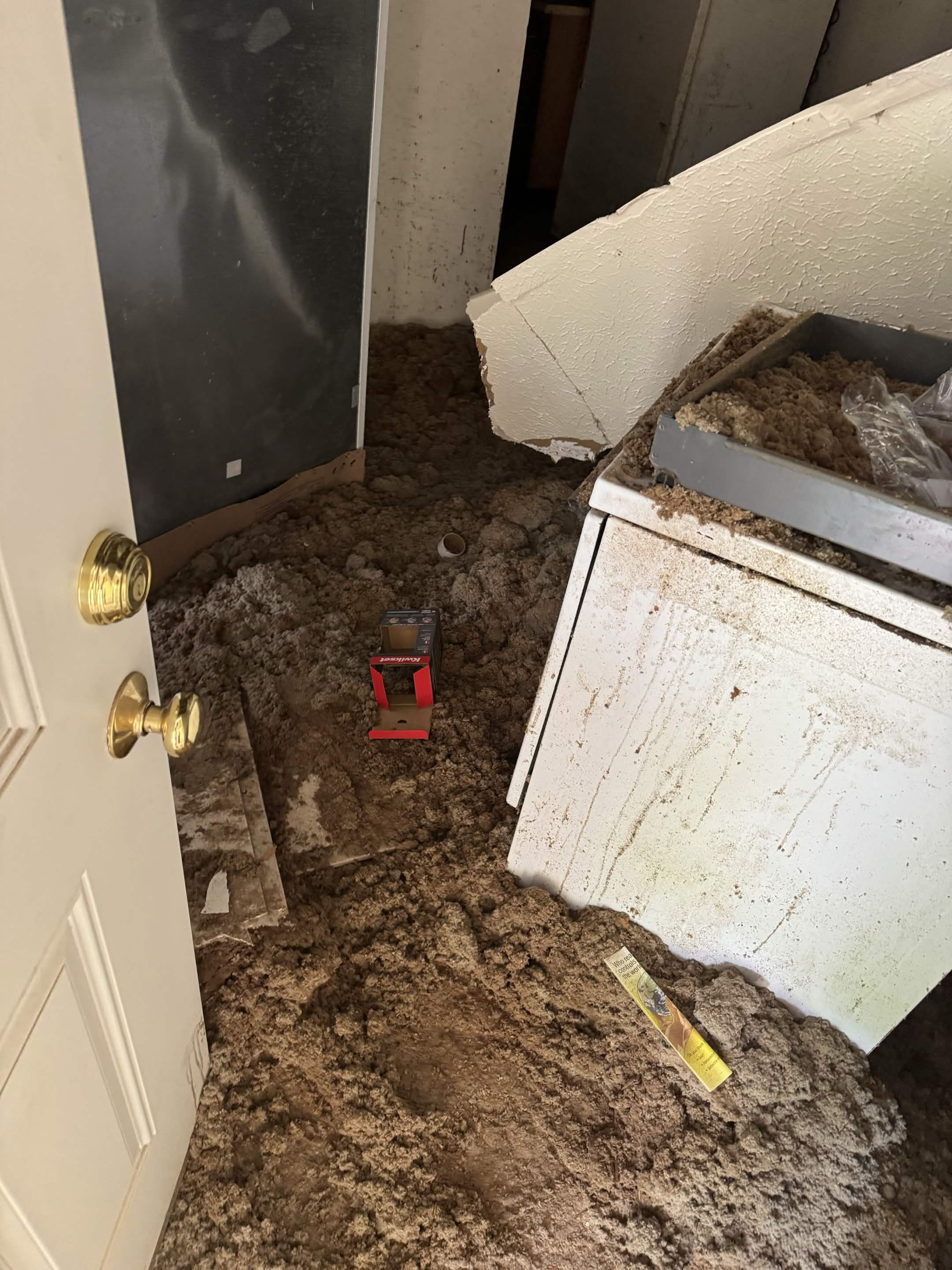 Laundry room floor buried in collapsed ceiling insulation and debris before junk removal