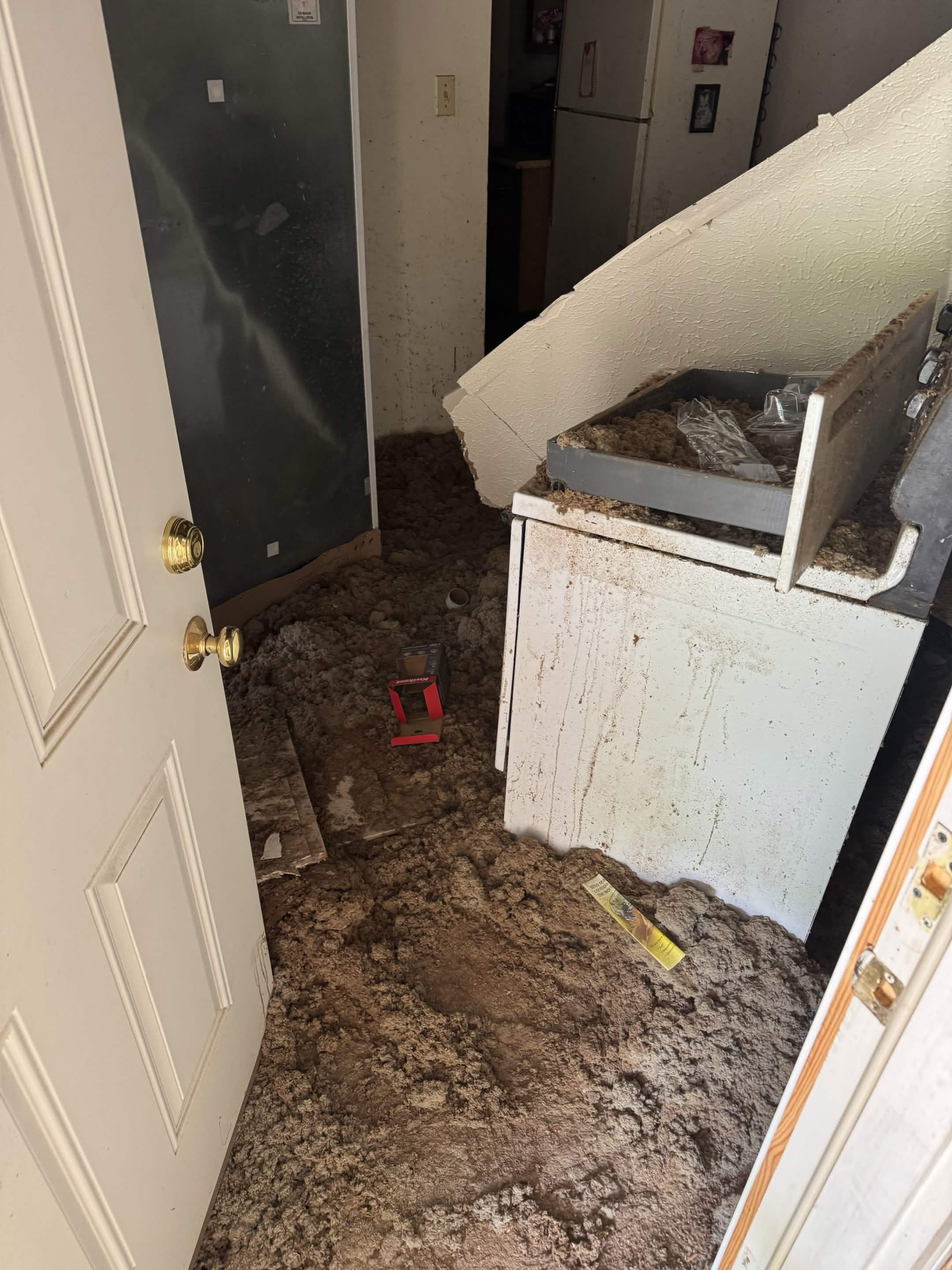 Utility room covered in fallen ceiling debris around a washer and dryer before junk removal