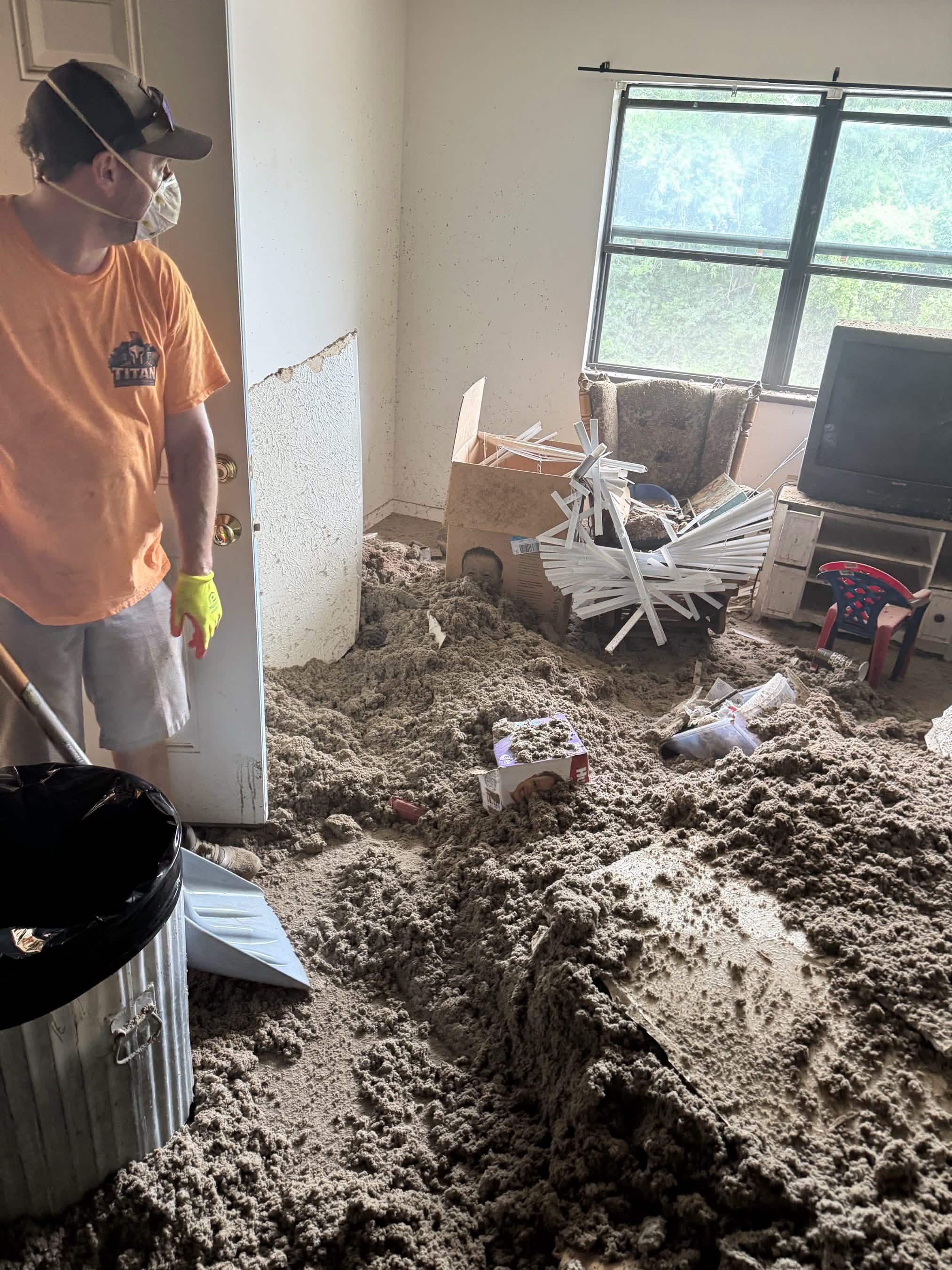 Titan crew member shoveling collapsed insulation into a can during a heavy debris cleanout